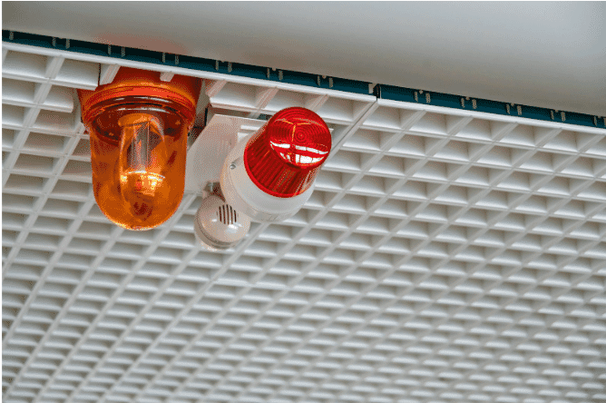 Emergency fire alarm system with red and amber warning lights mounted on a ceiling, highlighting the role of 2-hour fire-rated cables in maintaining functionality during fire emergencies, as detailed in the blog on safety and compliance