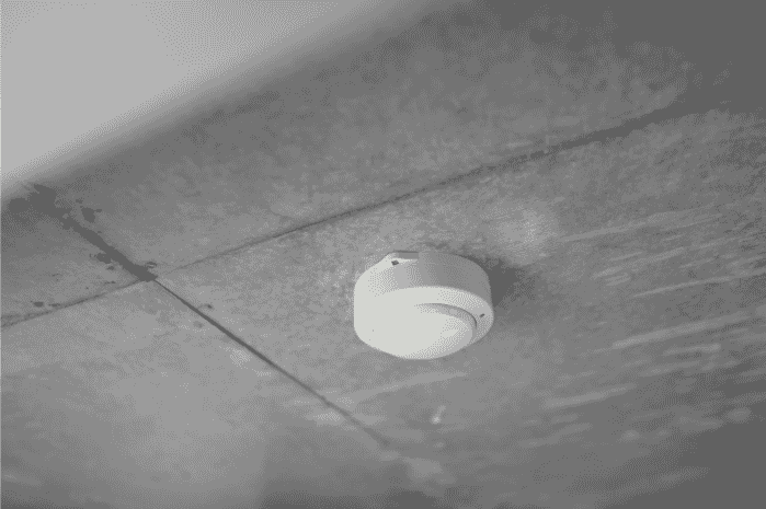 Fire alarm sensor mounted on a ceiling, highlighting the importance of using 2-hour fire-rated cables, fire alarm cables, and plenum cables for safety. Shielded cables and 2-conductor wires ensure reliable signal transmission in critical fire protection system