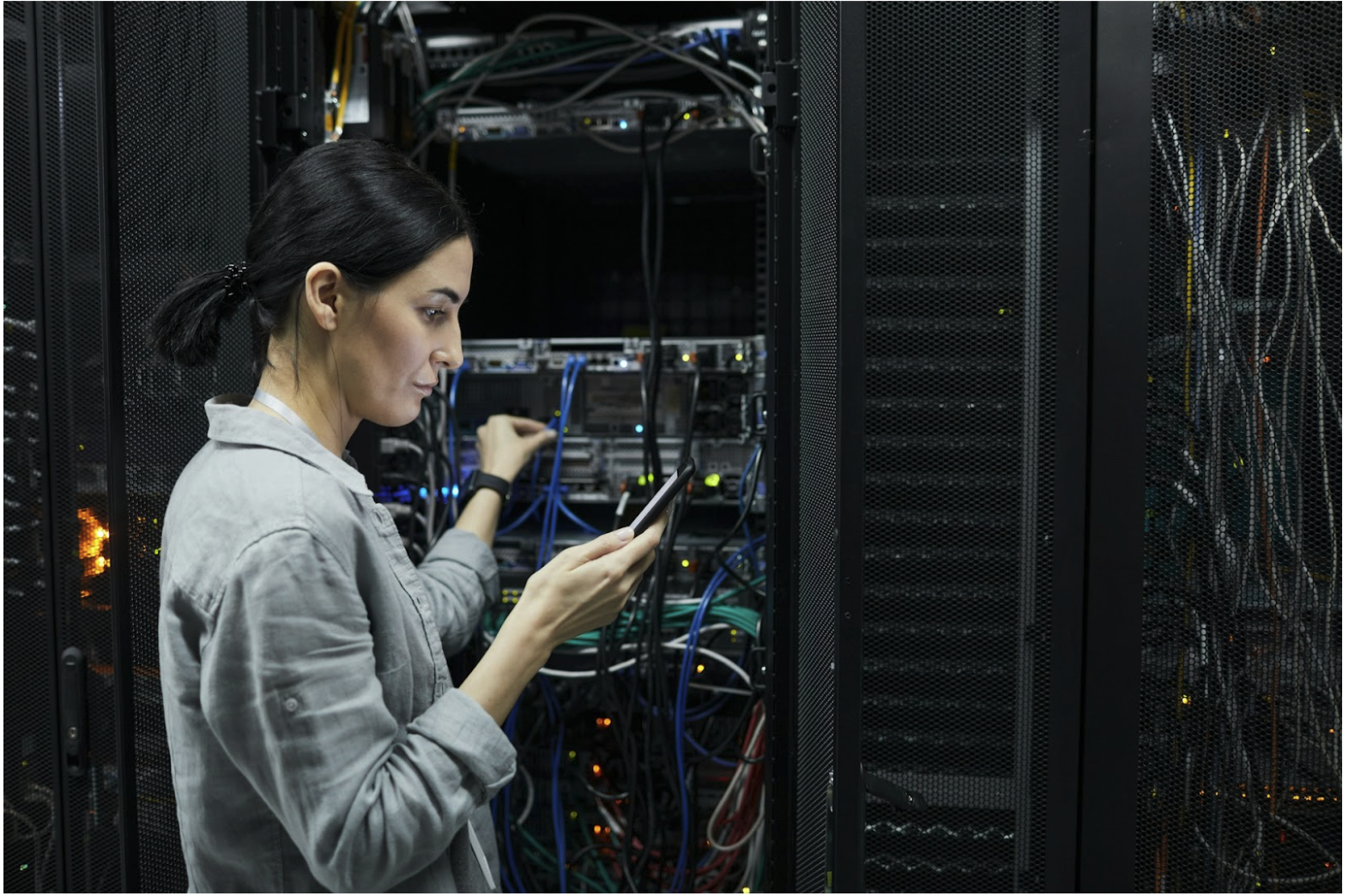 Technician working in a data center managing fiber optic connections, illustrating multimode fiber infrastructure and OM1 vs OM3 network performance in commercial environments