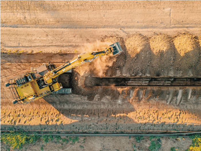 Top-down view of a heavy-duty excavator digging a trench for underground wiring installation, highlighting the scale and ruggedness required for high-performance industrial and commercial electrical systems