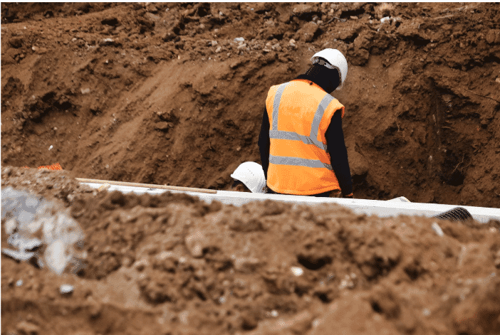 Construction workers in a trench preparing for underground installations, potentially using direct burial wire to ensure durability and protectio