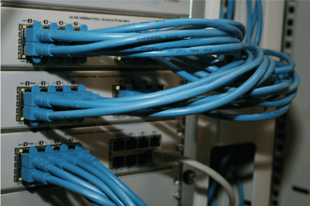 Close-up of blue Cat5 Ethernet cables connected to a network switch, emphasizing the importance of understanding maximum Ethernet cable length limits for network performance. Proper cable length helps prevent signal attenuation, reduce latency, and avoid interference, crucial for maintaining reliable and efficient business networks