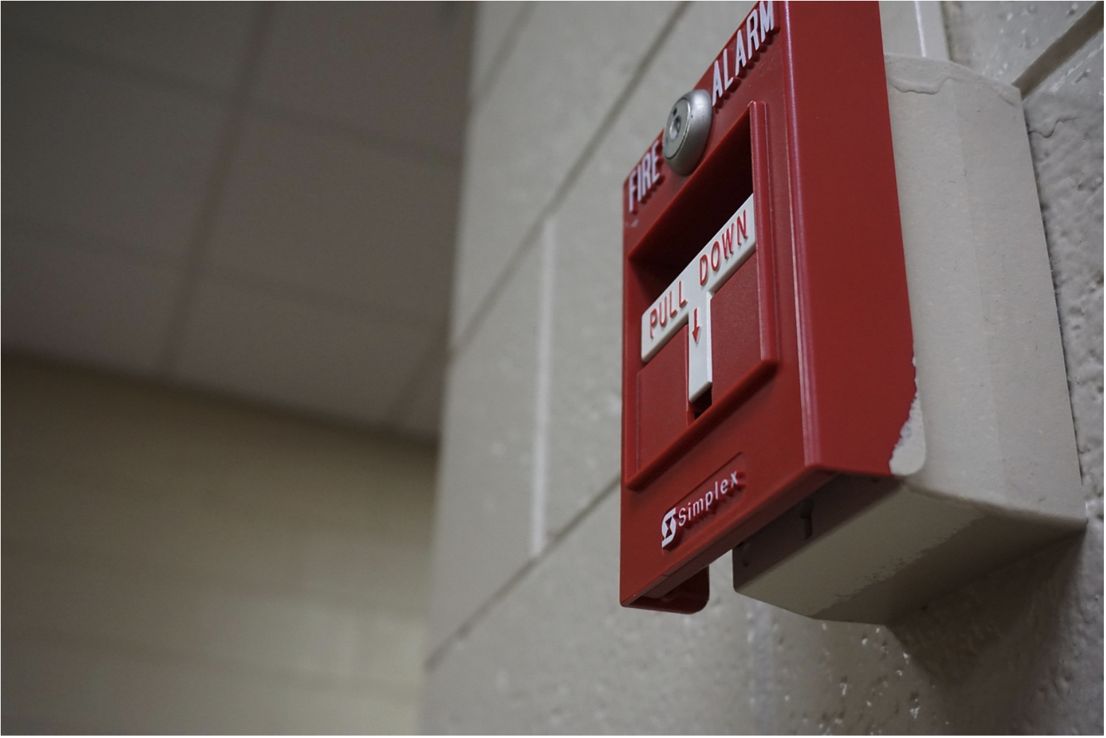 Fire alarm pull station mounted on a wall in a commercial building, representing life-safety systems supported by 2 hour fire cable and reliable signal continuity