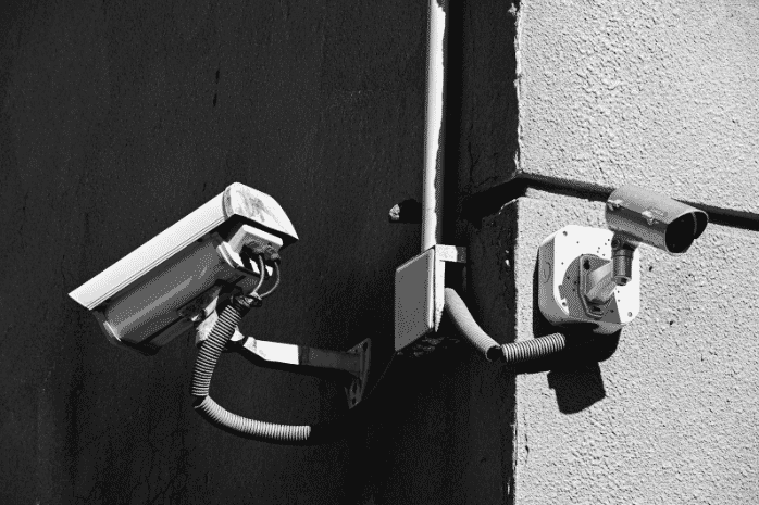 This image features two surveillance cameras mounted on a building corner, with cables securely routed along the wall. The setup highlights the use of shielded cables, ensuring signal integrity. The outdoor cables are resistant to weather conditions, making them ideal for access control systems