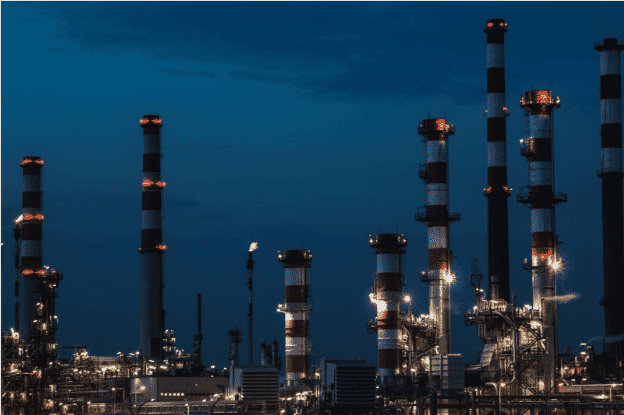 Industrial refinery facility at night showcasing the need for durable gas and oil-resistant cables. The image highlights environments where FEP cables, including FEP insulated oil-resistant cables, provide critical performance. These high-performance FEP wiring solutions offer chemical resistance and heat-resistant properties, ideal for harsh industrial applications that require long-lasting and reliable cables