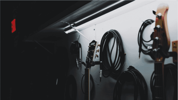 Wall-mounted collection of audio equipment, including coiled cables and guitars, symbolizing the importance of understanding balanced vs unbalanced audio cables