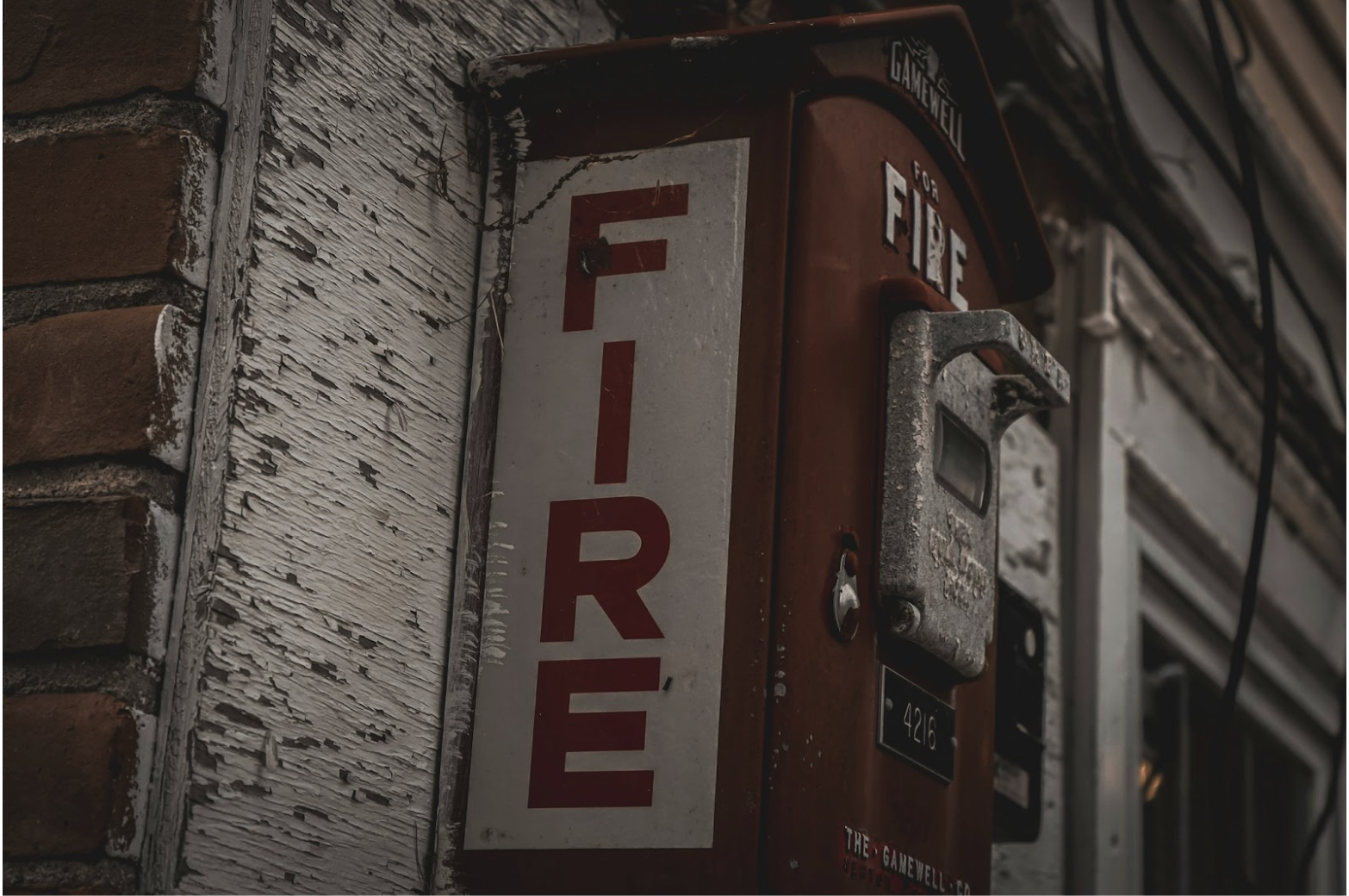 Exterior fire alarm call box mounted on building representing life safety communication systems supported by 2-hour fire alarm cable and circuit integrity wiring