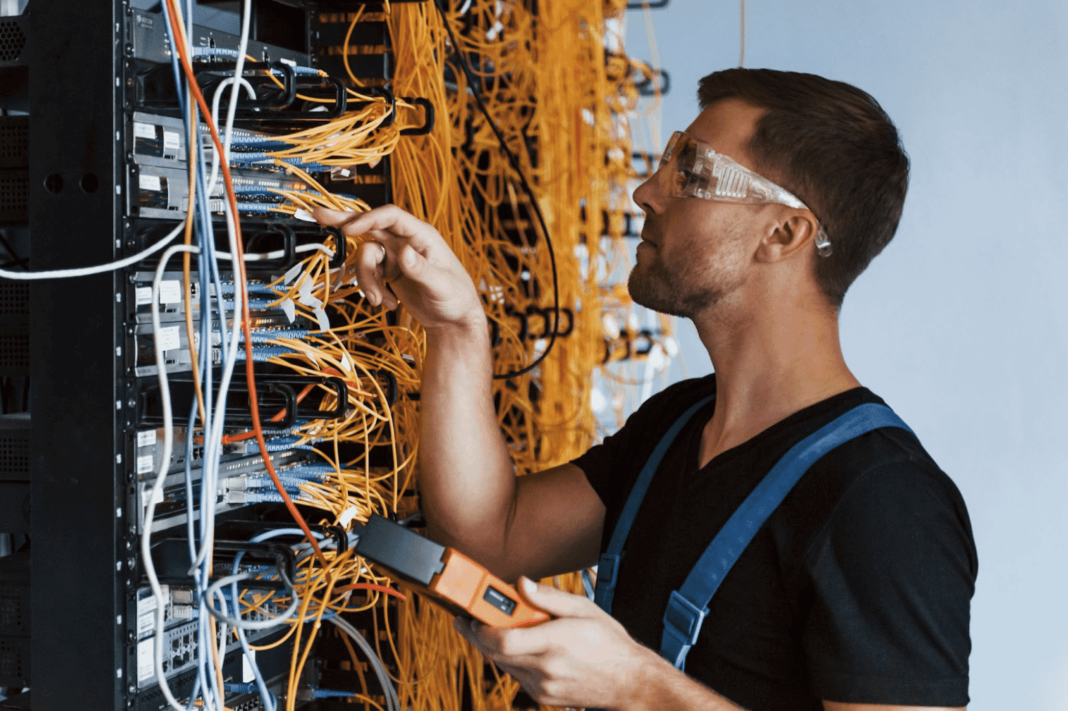 Technician working with network cabling, organizing and labeling data cables in a server room. The image shows a focused professional conducting cable testing and routing, ensuring the proper connection of CAT 6 wire and cable infrastructure
