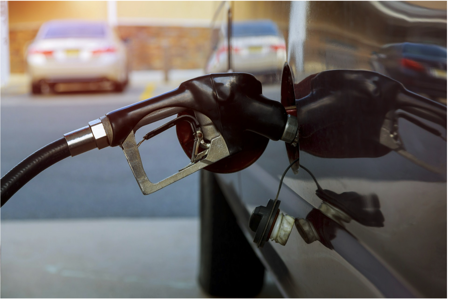 Fuel pump nozzle dispensing gasoline into vehicle, illustrating petroleum environments where cable ratings and oil-resistant construction support fuel system safety