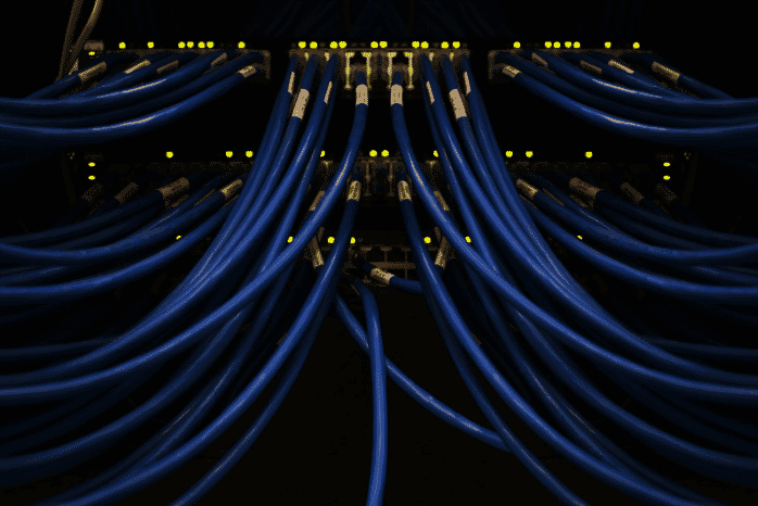 Close-up of blue indoor security cables connected in a data center, showcasing indoor-outdoor security wiring and durable outdoor cable solutions for robust and reliable network infrastructure