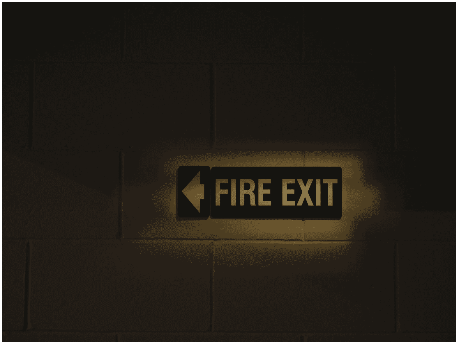Illuminated fire exit sign on a dark wall, symbolizing the importance of fire protection wiring solutions for safety and emergency preparedness in buildings