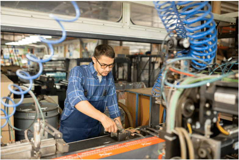 A factory worker operating industrial machinery with visible wiring, representing the durability and reliability of FEP-insulated oil-resistant cables in harsh environments
