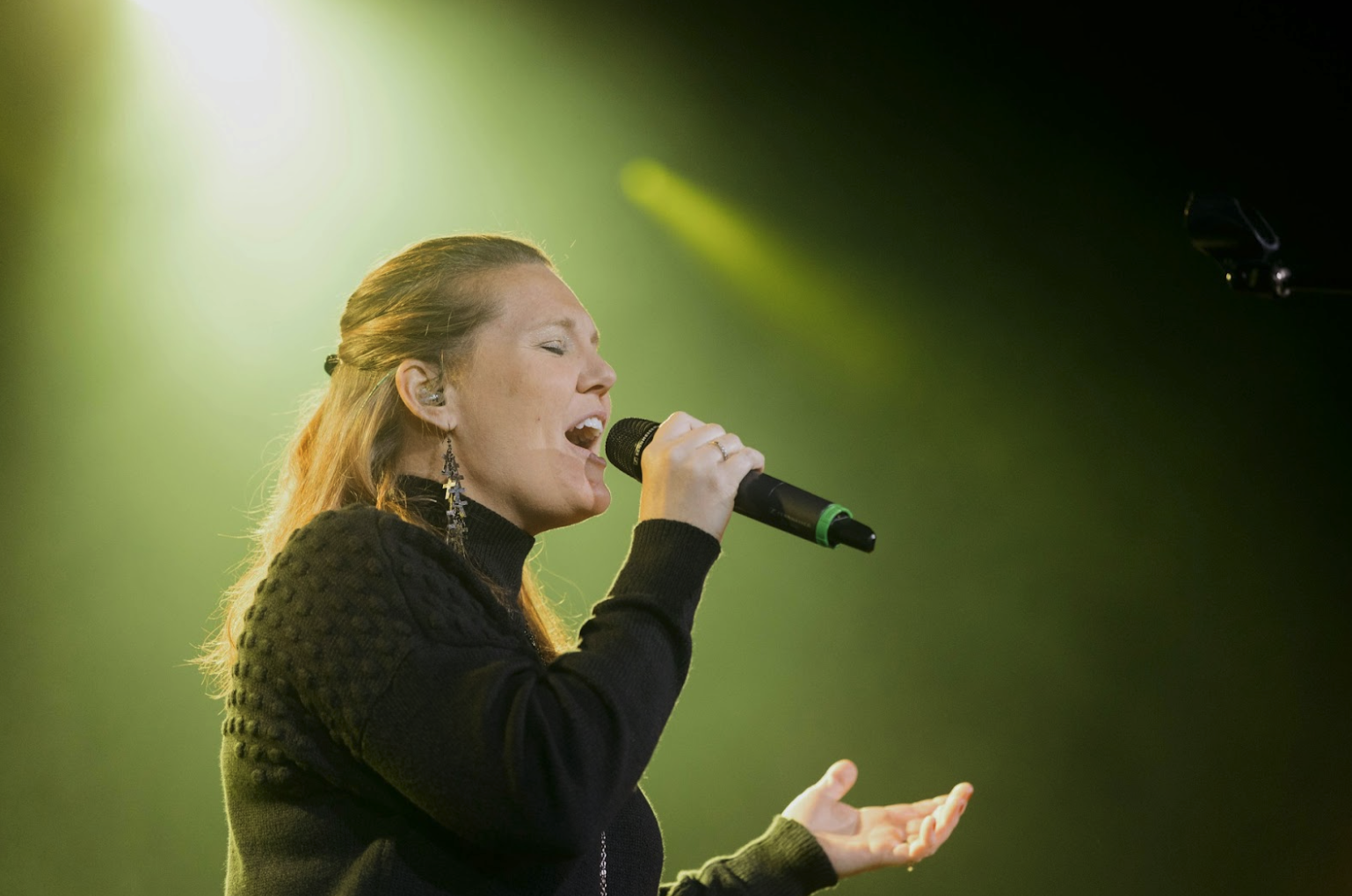 Performer using a wireless microphone in a professional audio system where mic line cabling supports the signal path.