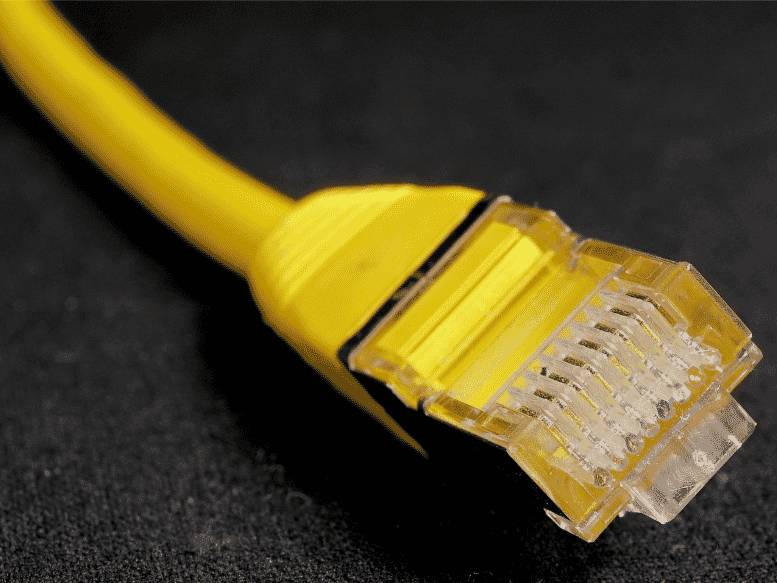 Close-up of a yellow shielded patch cable, showcasing its clear protective casing and internal wiring, emphasizing its role in providing superior signal integrity and data security in high-EMI environments
