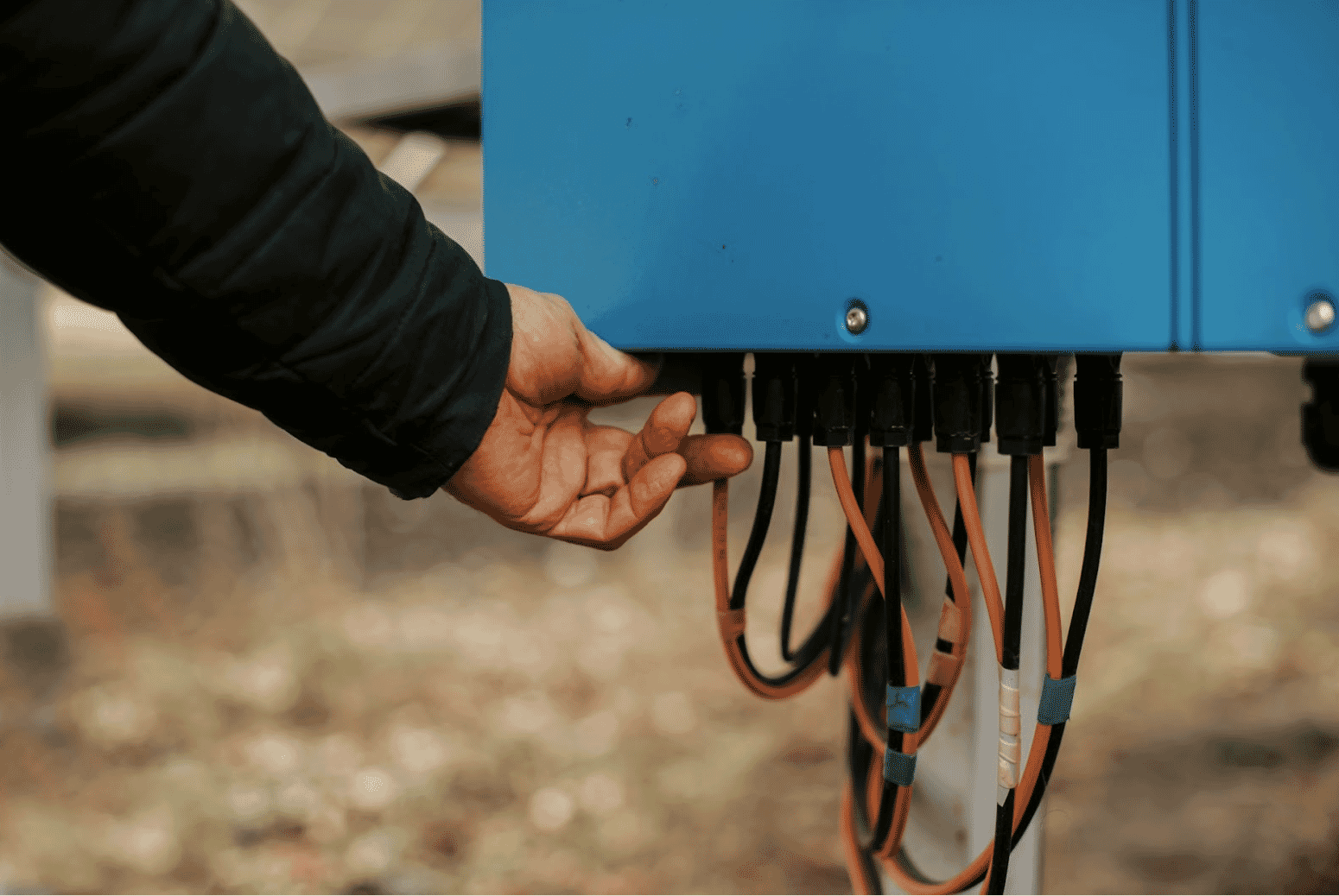 Technician adjusting UV-resistant and moisture-resistant electrical cables connected to a blue weatherproof junction box, demonstrating best practices for outdoor electrical installations as recommended by Windy City Wire