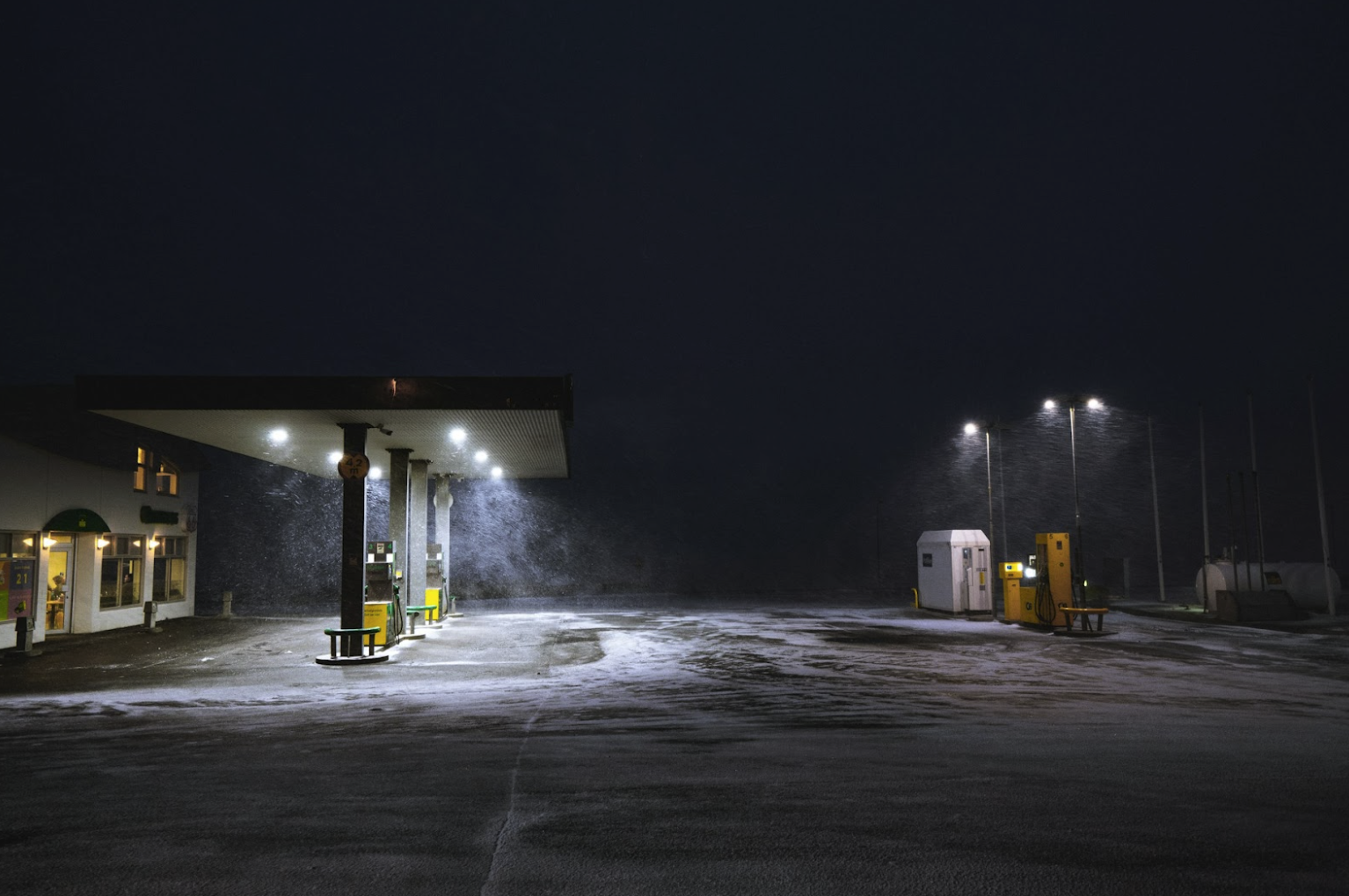 Snow blowing across a commercial fuel station at night, illustrating the harsh petroleum environment where oil-resistant wire must withstand moisture, temperature stress, vibration, and fuel exposure.