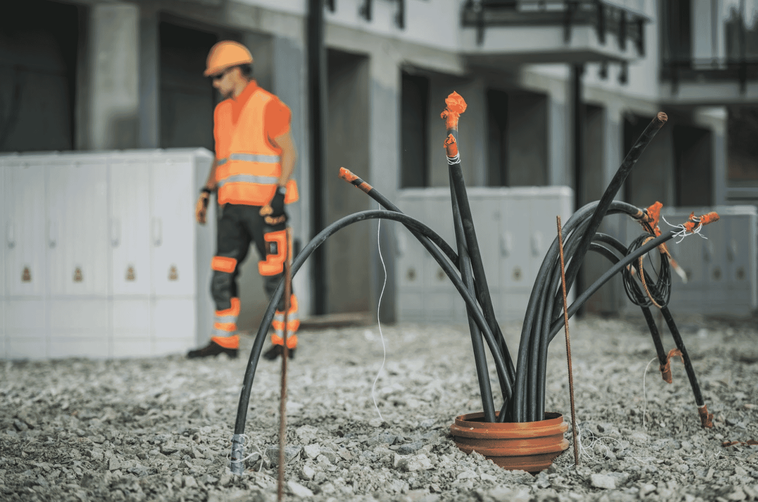 Construction worker in high-visibility gear standing near exposed cables on a construction site, illustrating the rugged and durable nature of these cables designed for outdoor and underground use