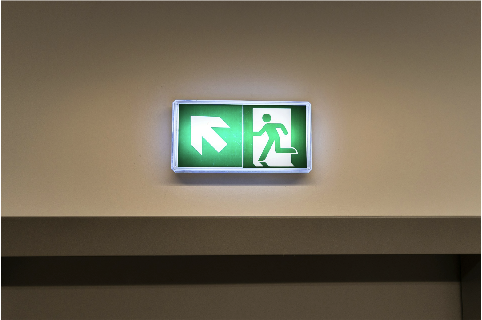 Illuminated emergency exit sign in commercial building, illustrating life safety systems that rely on 2-hour fire rated cable for circuit integrity during emergencies