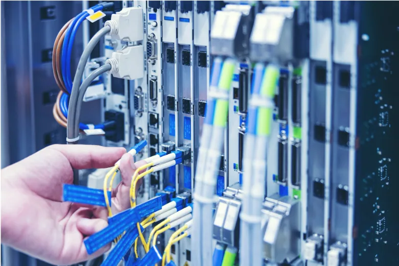 Technician connecting cables in a commercial network equipment rack, the structured cabling environment where choosing the right RJ45 connector affects performance