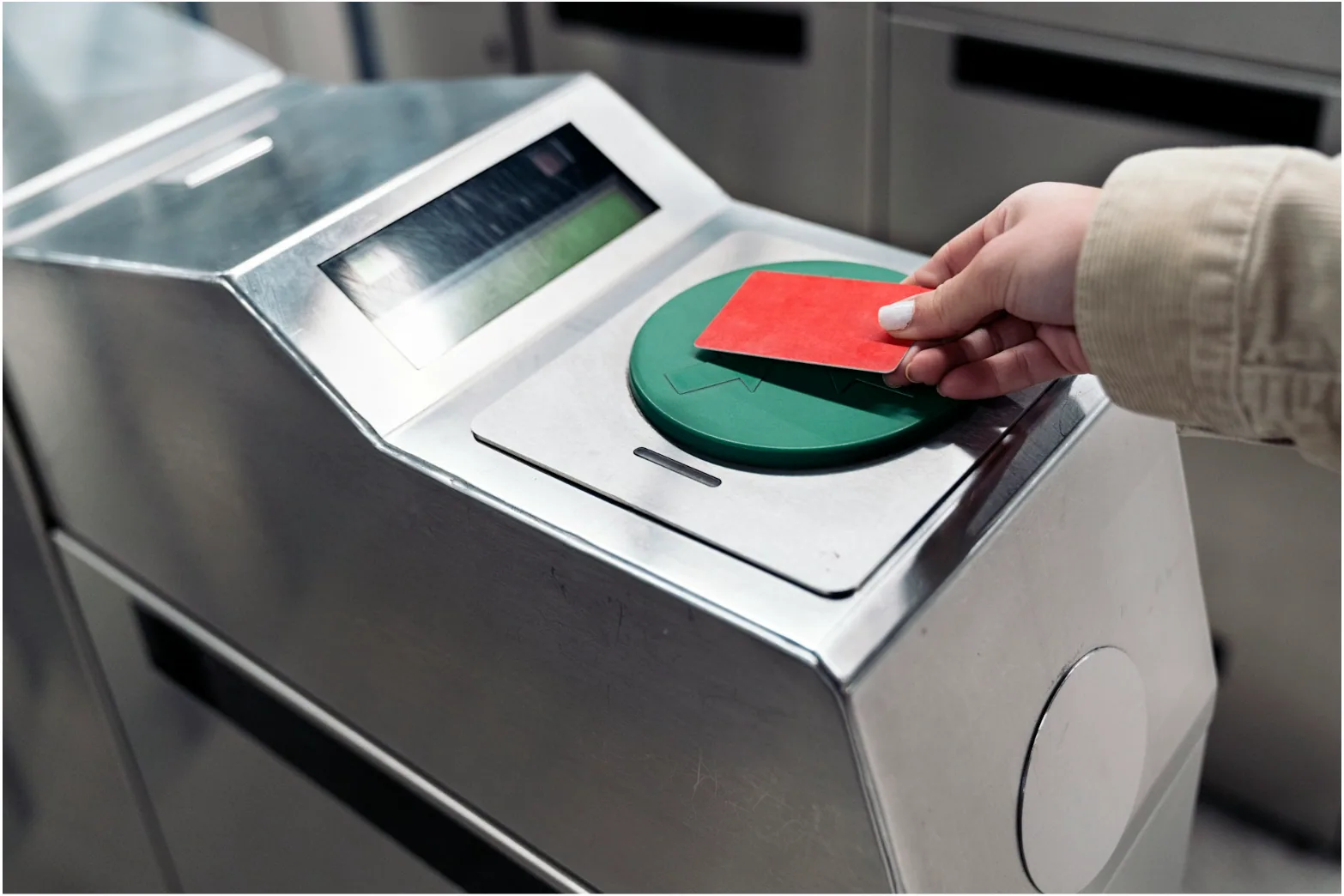 Hand tapping an access card on a green contactless card reader mounted on a security turnstile, the type of access control hardware wired with 18 AWG 6-conductor security cable