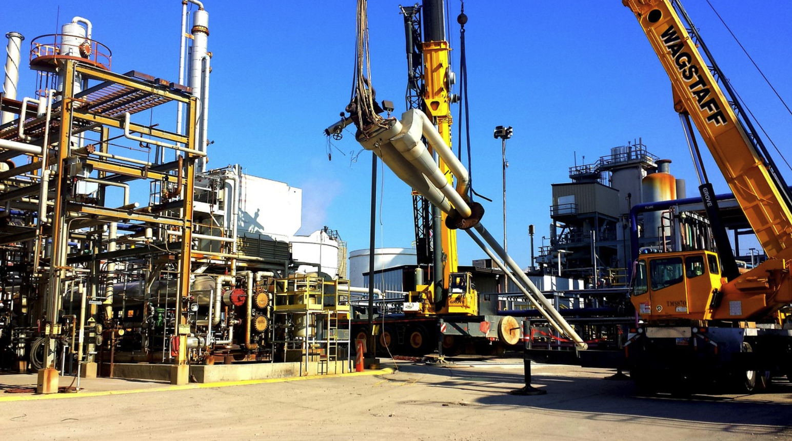 Industrial oil refinery with process piping and heavy machinery in harsh oil and gas environment.
