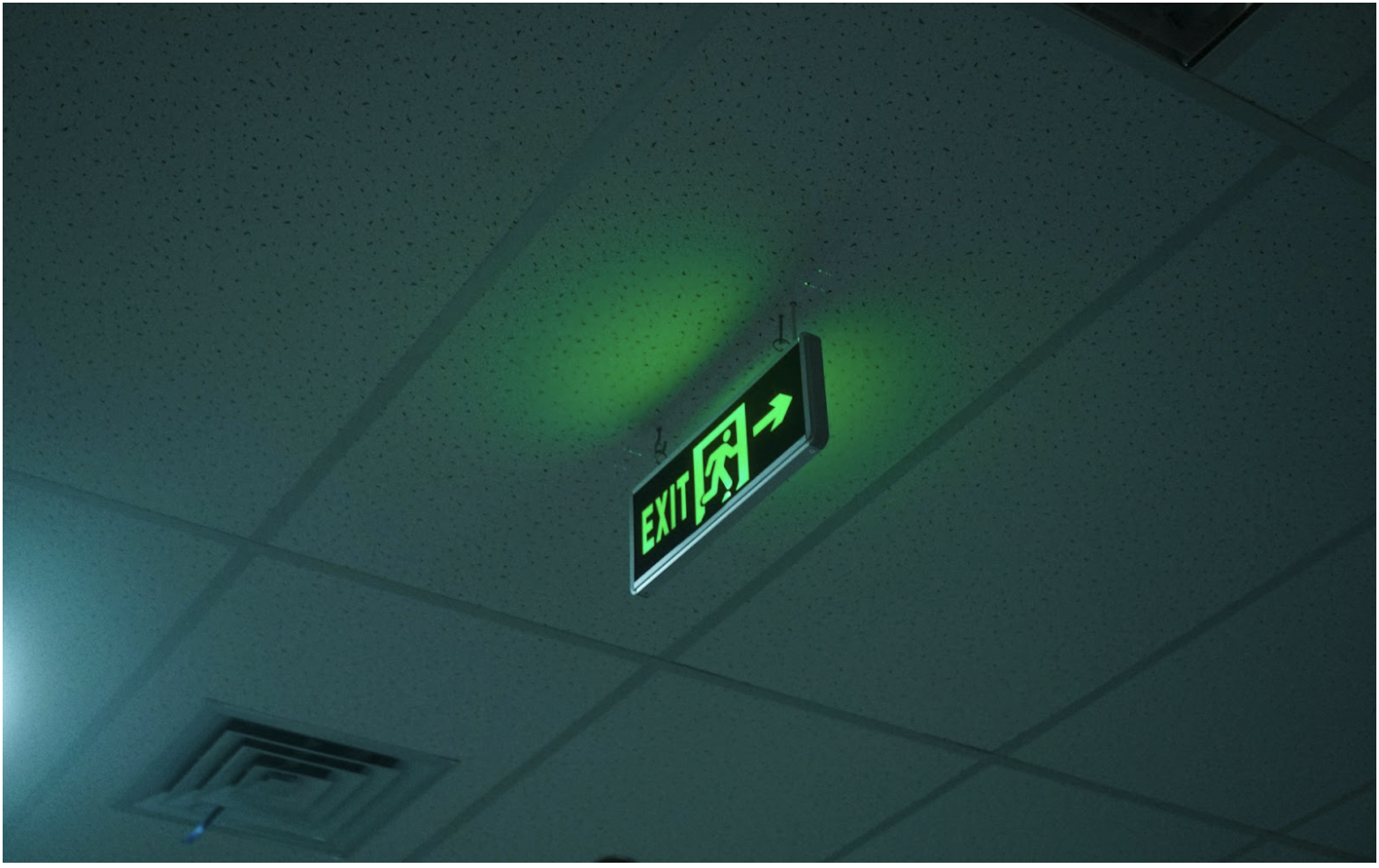 Green illuminated emergency exit sign in a commercial building, representing life-safety systems supported by 2 hour fire cable and fire rated cable