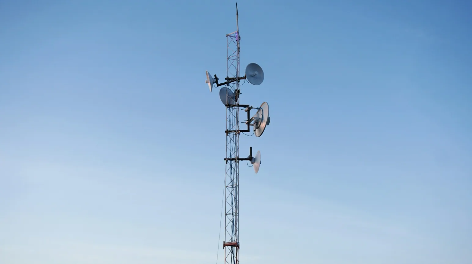 Communications tower with multiple antennas and microwave dishes supporting digital media signal transmission for wireless broadcast, satellite, and RF communication systems.
