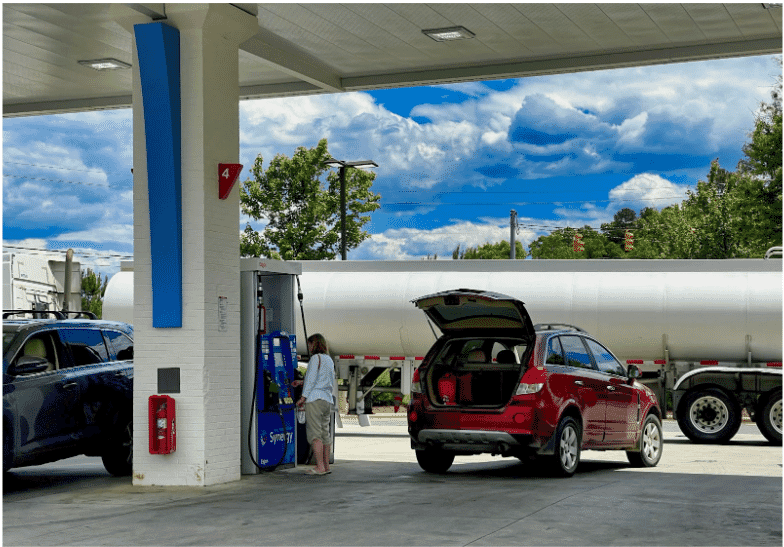 A gas station with multiple cars refueling and a fuel tanker is parked, showcasing the importance of underground storage tank cables in our daily lives