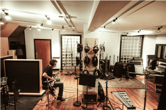 A professional recording studio with a musician playing an electric guitar, showcasing the importance of low-noise MIC cables for clear audio recording