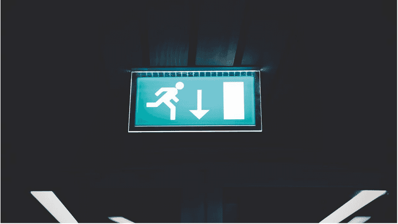 Illuminated exit sign in a dimly lit environment, symbolizing emergency pathways where 2-hour fire-rated cables are essential for maintaining functionality of safety systems during fire incidents.