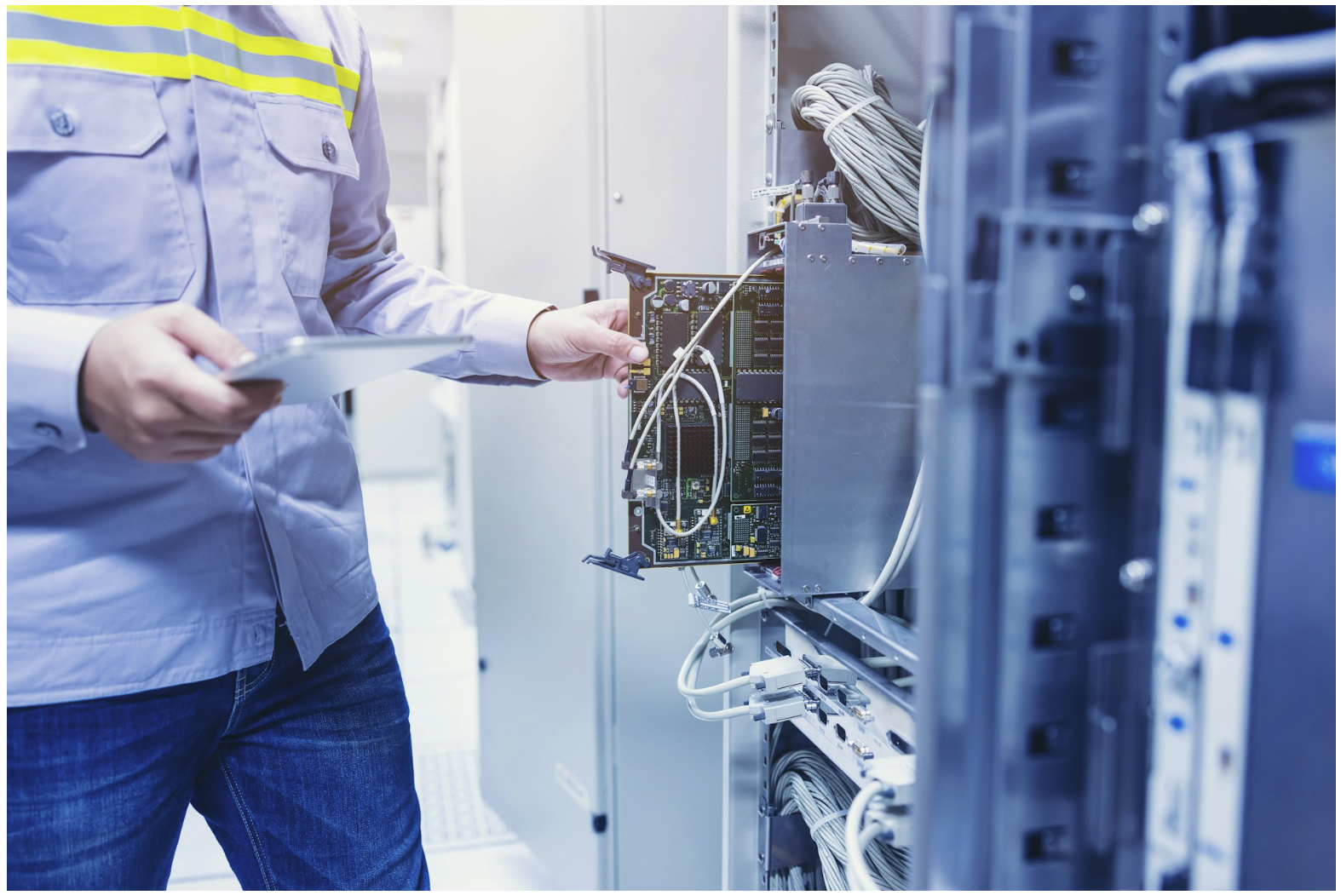 Technician connecting Ethernet cables in network equipment rack, illustrating structured cabling and how connectors impact maximum cable length in commercial networks