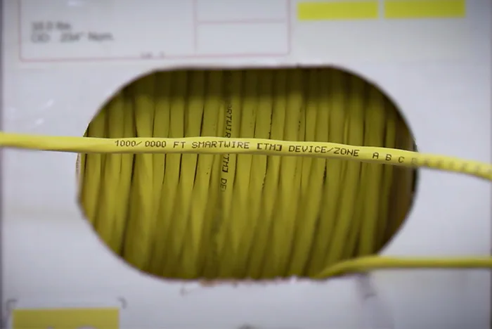SmartWire cable exiting a dispenser box with sequential footage markings printed on the jacket for easy run planning.